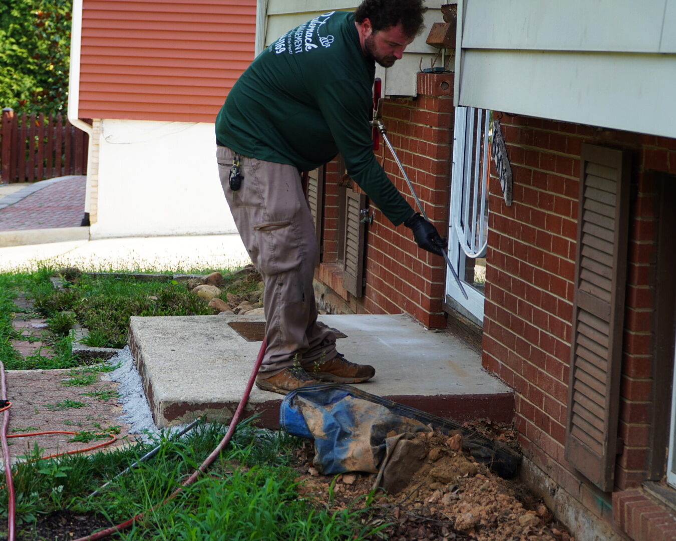 Erik Pasternack treating the foundation and entry points of a brick home in Maryland
