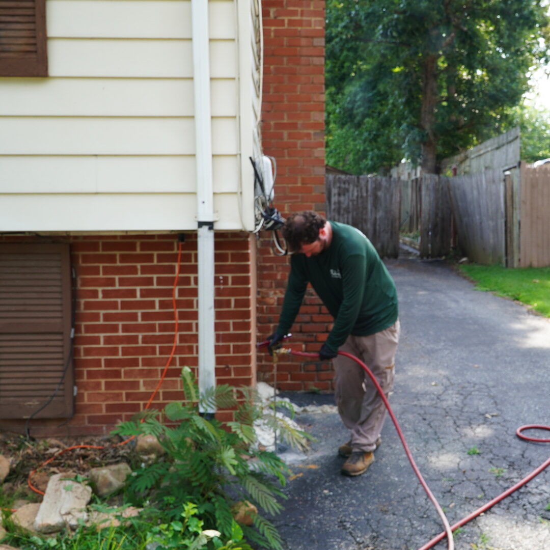 Pasternack Pest Management technician on an exterior service visit at a Maryland brick home