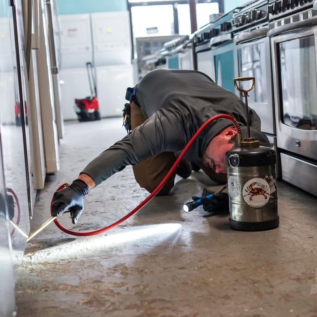 Pasternack Pest Management technician treating along the base of appliances during an interior pest service